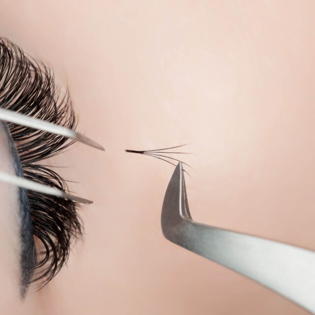 Eyelash extension procedure close up. Beautiful Woman with long lashes in a beauty salon.